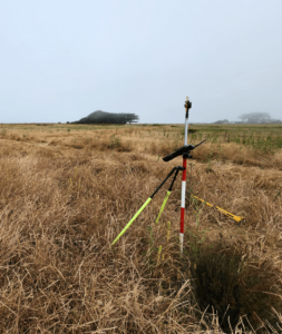 Land surveying in a field under overcast skies